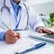 hands-unrecognizable-female-doctor-writing-form-typing-laptop-keyboard-2048x1367