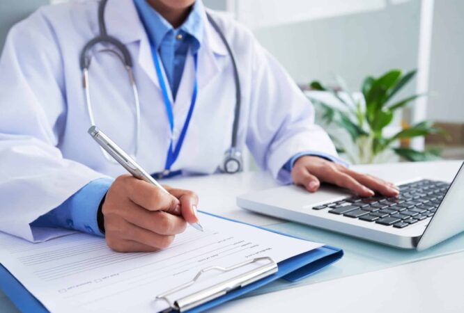 hands-unrecognizable-female-doctor-writing-form-typing-laptop-keyboard-2048x1367